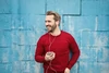 Homme en pull rouge souriant avec des écouteurs